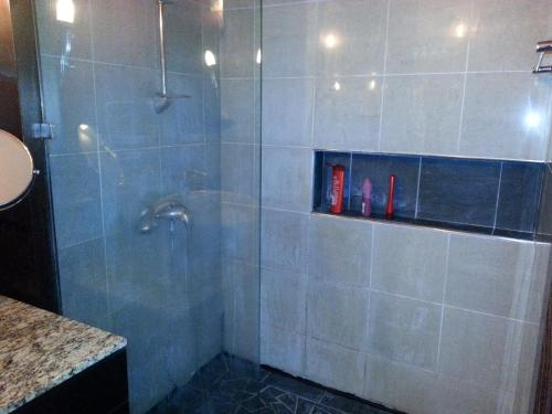 a bathroom with a shower with a glass door at Toupidek-sur-la-Plage in Arue