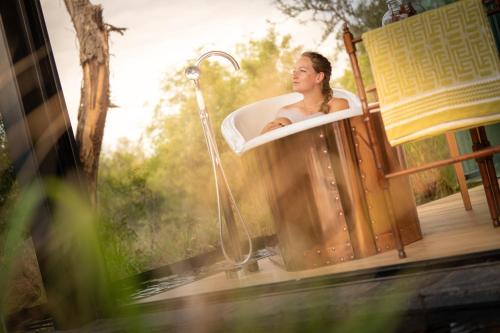 a woman sitting in a bathtub in a porch at Monwana in Thornybush Game Reserve