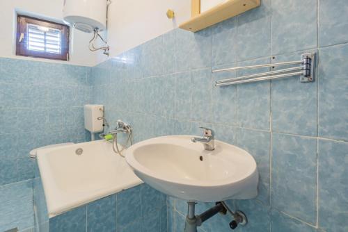 ein blau gefliestes Bad mit einem Waschbecken und einem Spiegel in der Unterkunft Lucija with mountain and seaview in Metajna