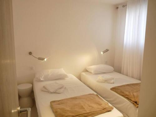 deux lits dans une petite pièce aux murs blancs dans l'établissement Two bedroom apartment next to the Croisette in Cannes a short walk to the Palais des Festivals - 1961, à Cannes