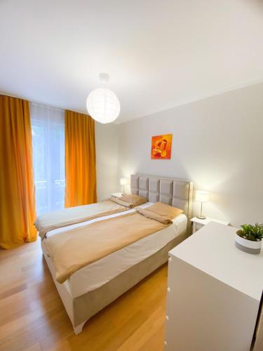 a bedroom with a large bed with orange curtains at Sunny apartment in Bečići