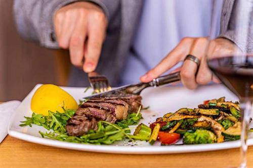a person cutting a plate of food with a steak at Hotel Casa Maria in Halblech