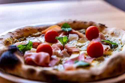 a pizza with tomatoes on a plate on a table at Hotel Casa Maria in Halblech