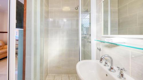a white bathroom with a shower and a sink at Across Country Motor Inn in Dubbo