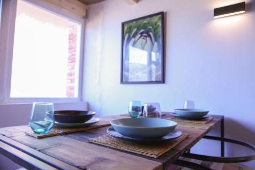 a wooden table with bowls and glasses on it at Apartamentos BocairentHomes, en pleno centro de Bocairent, con pequeña piscina y parking privado in Bocairent