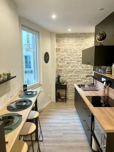 une cuisine avec deux lavabos et un mur en pierre dans l'établissement APPARTEMENT 1 CHAMBRE AVEC ENTREE INDIVIDUEL, à Chalon-sur-Saône