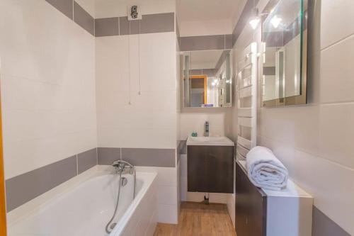 une salle de bain blanche avec une baignoire et un lavabo dans l'établissement Les Dryades - Appartement lumineux avec grand balcon et vue sur la montagne, à Les Allues