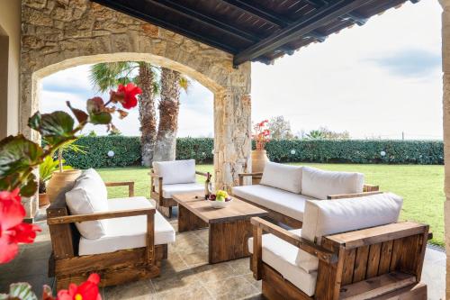 a patio with chairs and tables and a stone wall at Palmrise Luxury Villas by Travel Pro Services - Nea Skioni Halkidiki in Nea Skioni