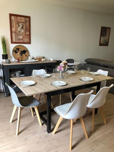 une table en bois avec des chaises blanches et une table en bois dans l'établissement Superbe Appartement, à Saumur