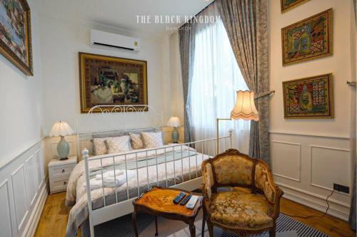 a bedroom with a bed and a chair and a table at The Black Kingdom - เดอะ แบล็ค คิงดอม in Bangkok