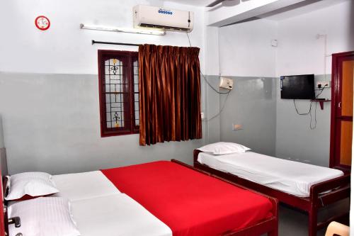 um quarto com 2 camas e uma janela com um cobertor vermelho em LRR TOWERS(LODGE) em Dindigul