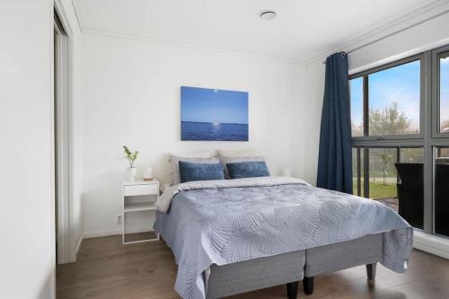 ein weißes Schlafzimmer mit einem Bett und einem Fenster in der Unterkunft Moderne leilighet - nært flyplass - lader for elbil in Råholt