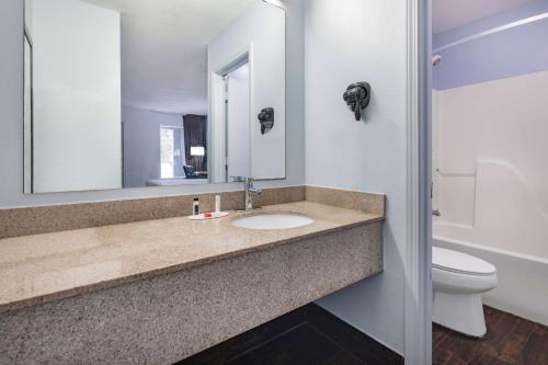 a bathroom with a sink and a toilet and a mirror at Days Inn by Wyndham Pensacola I-10 in Pensacola