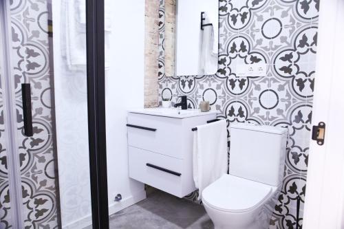 a bathroom with a toilet and a sink and a mirror at Apartamentos BocairentHomes, en pleno centro de Bocairent, con pequeña piscina y parking privado in Bocairent