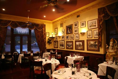 a dining room with tables and chairs with white table settings at Tamasha Hotel in Bromley
