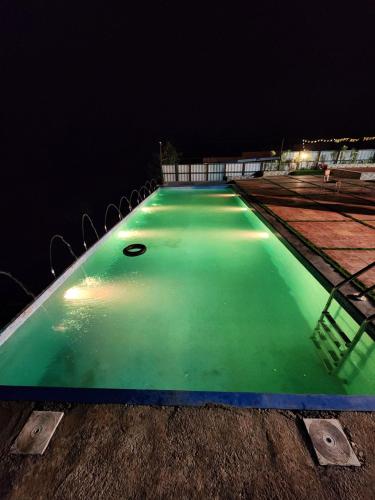a swimming pool at night with green illumination at Hilltop Resort and Glamping Wai, Near Panchgani in Wai