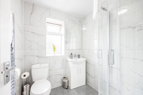 uma casa de banho branca com um WC e um chuveiro em Newly Launched 2 Bed Home in Dagenham ~London with free Wifi & Off-Street Parking em Goodmayes