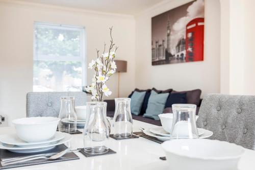 una mesa de comedor con platos blancos y jarrones de cristal en Newly Launched 2 Bed Home in Dagenham ~London with free Wifi & Off-Street Parking en Goodmayes
