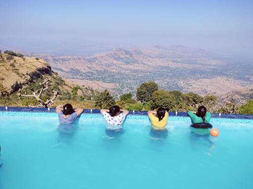 um grupo de três raparigas sentadas numa piscina em Hilltop Resort and Agro Tourism Wai, Near Panchgani em Wai