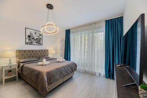 sypialnia z łóżkiem z niebieskimi zasłonami i telewizorem w obiekcie Blue Moon Apartments w Braszowie
