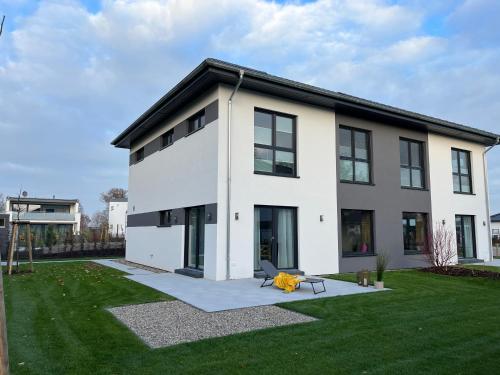 una grande casa bianca con un cortile verde di NEU! Feriendomizil TraumZeit 2 mit Sauna & Garten a Göhren-Lebbin