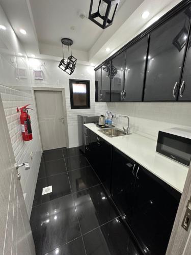 una cocina con armarios en blanco y negro y fregadero en Blue Rose Hotel, en Al Amarat