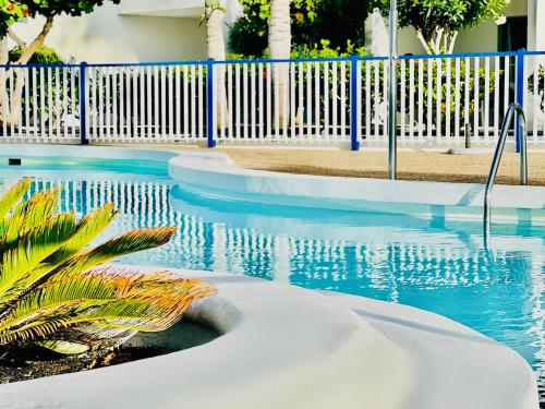 a swimming pool with blue water and a white fence at Canaryislandshost l Sal de Mar in Puerto del Carmen