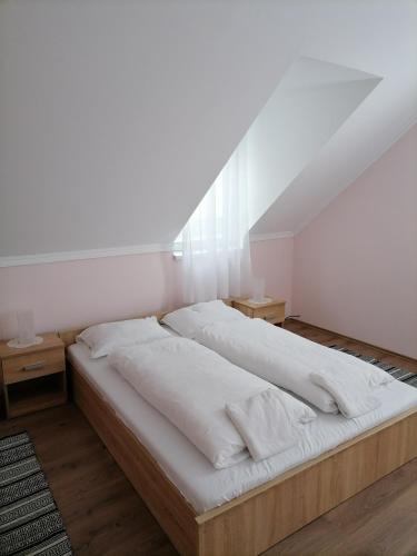a bedroom with a large bed with white sheets at Jázmin Vendégház 