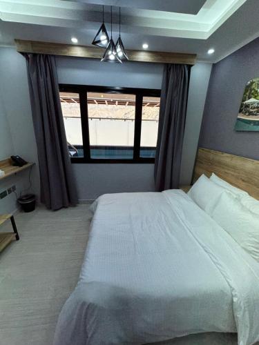 a bedroom with a large bed and a window at Blue Rose Hotel in Al Amarat