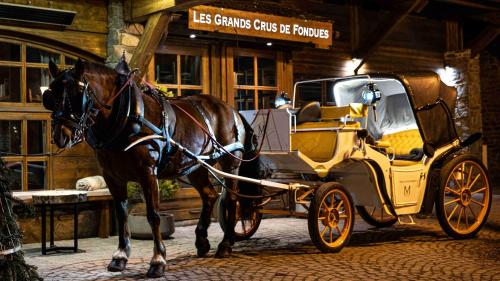 a horse pulling a carriage in front of a building at M de Megève in Megève