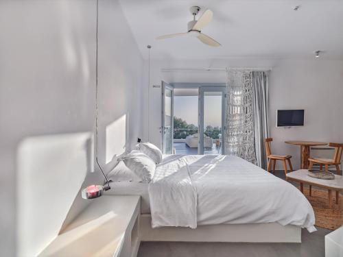 a white bedroom with a bed and a dining room at Santorini Heights in Pirgos