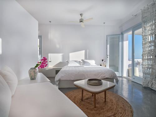 a white bedroom with a bed and a table at Santorini Heights in Pirgos