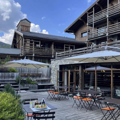 a patio with tables and umbrellas in front of a building at M de Megève in Megève
