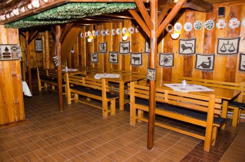 a restaurant with wooden walls and wooden benches and plates on the wall at Pensiunea Casa Maria in Săpînţa