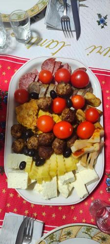 a plate of food on a table with tomatoes and meats at Pensiunea Piatra Mandrutului in Scărişoara