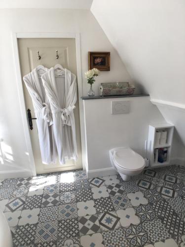 a white bathroom with a toilet and a door at La Romance et la Romanesque in Berville-sur-Mer