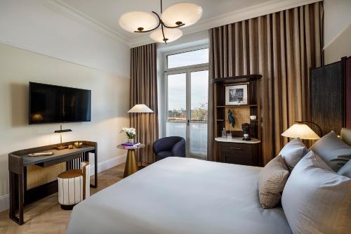 a hotel room with a bed and a desk and a window at Small Luxury Hotel Ambassador Zurich in Zürich