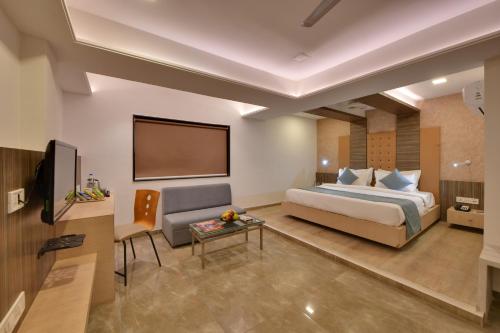 Habitación de hotel con cama y TV de pantalla plana. en Click Hotel by Suba, Jamnagar, en Jamnagar