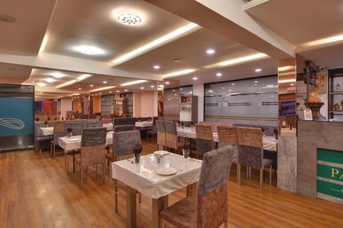 a restaurant with tables and chairs in a room at Click Hotel by Suba, Jamnagar in Jamnagar