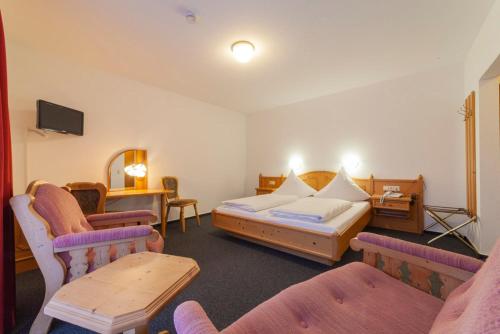 a hotel room with a bed and two chairs at Hotel & Landgasthaus Pfeifertal in Eulenbis