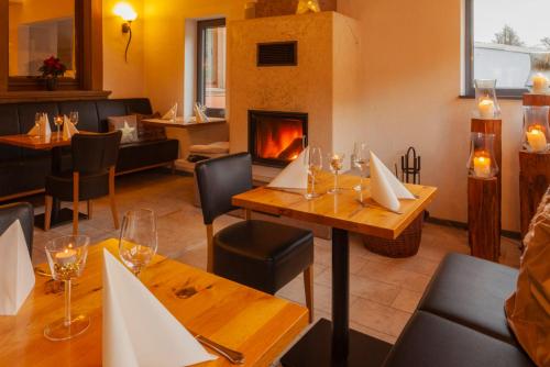 un restaurante con chimenea, mesas y sillas en Hotel & Landgasthaus Pfeifertal en Eulenbis