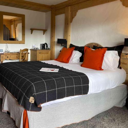 a bedroom with a large bed with orange and black pillows at M de Megève in Megève