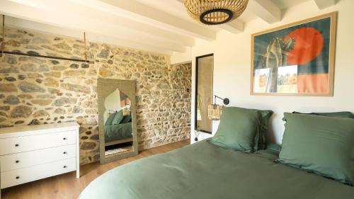 ein Schlafzimmer mit einer Steinmauer und einem Bett in der Unterkunft Le Ranch Kabahina Golf in Saint-Geours-de-Maremne