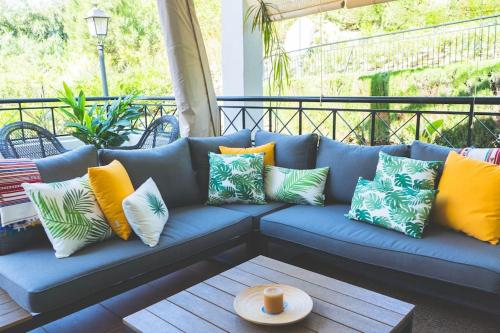 een blauwe bank met kleurrijke kussens op een veranda bij Precioso Apartamento 3hab. cerca de Puerto Banus in Marbella