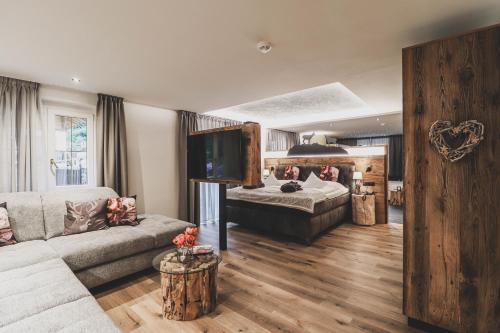 sala de estar con sofá y cama en Hotel Pfeldererhof Alpine Lifestyle, en Moso in Passiria