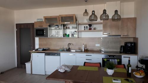 a kitchen with white cabinets and a wooden table at Apartman M5 Horní Mísečky in Horni Misecky
