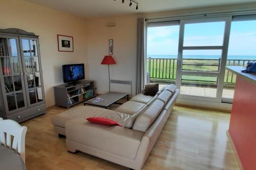 ein Wohnzimmer mit einem Sofa und einem TV in der Unterkunft exceptionnel penthouse vue mer in Wimereux