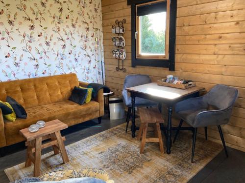 uma sala de estar com um sofá e uma mesa em Landelijk gelegen houten huisje em Opperdoes