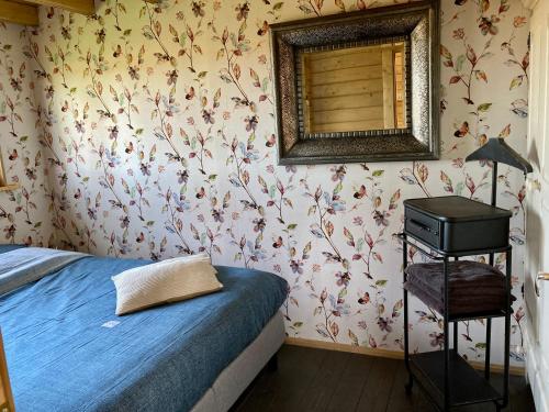 Schlafzimmer mit einem Bett und einem Wandspiegel in der Unterkunft Landelijk gelegen houten huisje in Opperdoes