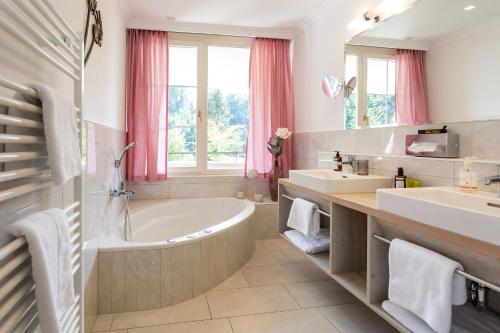 a bathroom with two sinks and a bath tub and a mirror at Boutiquehotel Bergvilla in Dafins